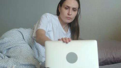 Exhausted Woman Finishing Work on Laptop Falls Asleep in Bed