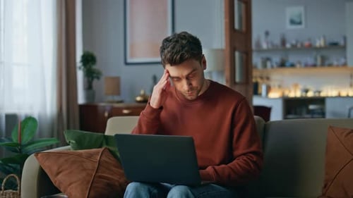 Man Using Laptop While Sitting on Sofa at Home