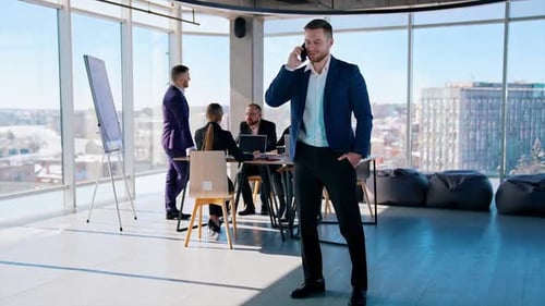 Young businessman in modern office room. Handsome man entrepreneur talking the phone next to the gro