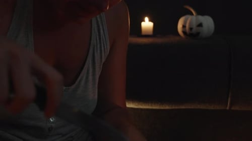 Woman Carving a Pumpkin by Candlelight for Halloween