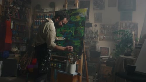 Artist Looking through Can of Brushes while Painting in Workshop