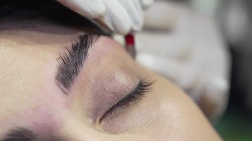 Woman receiving eyebrow shaping treatment close up