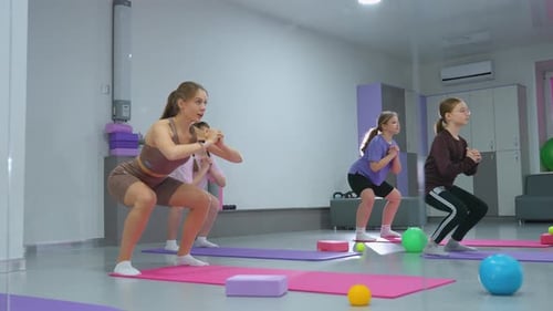 Group Workout Session Squatting and Positioning for PushUps in Fitness Studio