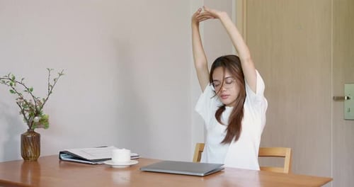 Woman Stretching at Desk before Working on Laptop
