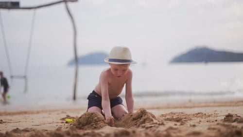 Boy Digging And Throwing Sand On A Beach