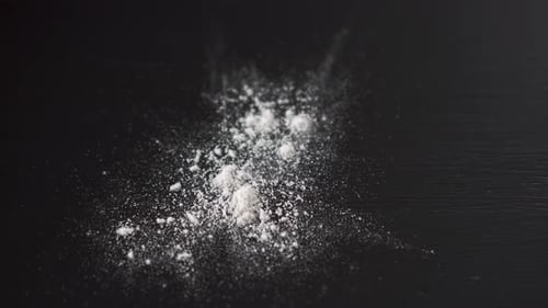 White powder falling on top of a table, crushed pills.