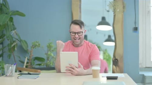 Man Celebrating While Using a Tablet Indoors