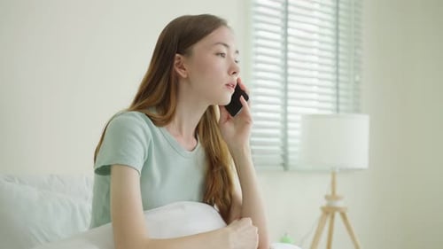 Distressed Woman Talking on Cell Phone in Bed