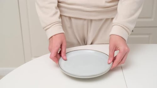 Person holding an empty ceramic plate on a white table. Close-up photography for design and print