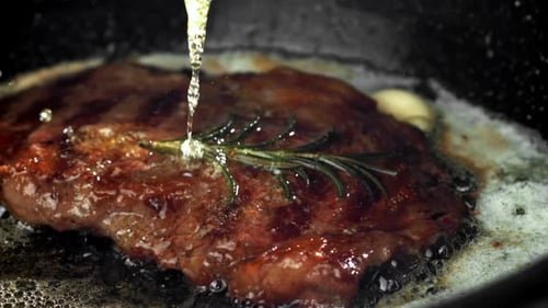 Cooking Steak With Herbs and Garlic in Pan