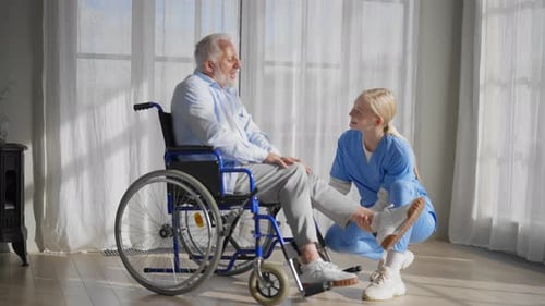 Kind Nurse Examining Senior Man in Wheelchair