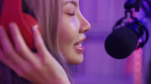 Woman Talking into Microphone Wearing Headphones