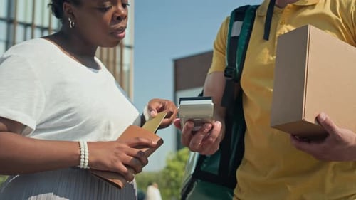 Black Woman Paying by Credit Card for Her Parcel to Deliveryman