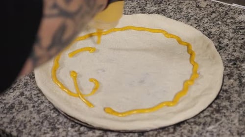 The Chef Applying Yellow Sauce to the Pizza Dough in the Restaurant Kitchen