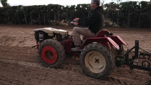 Man driving tractor plowing field in rural landscape