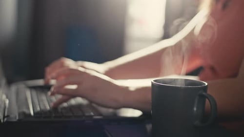 Closeup of Female Hands Making Friends on a Laptop and a Cup of Coffee