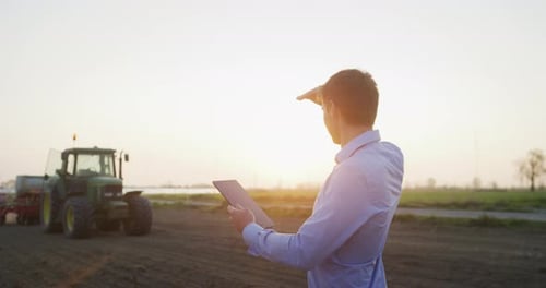 Farmer Using Tablet in Field at Sunrise