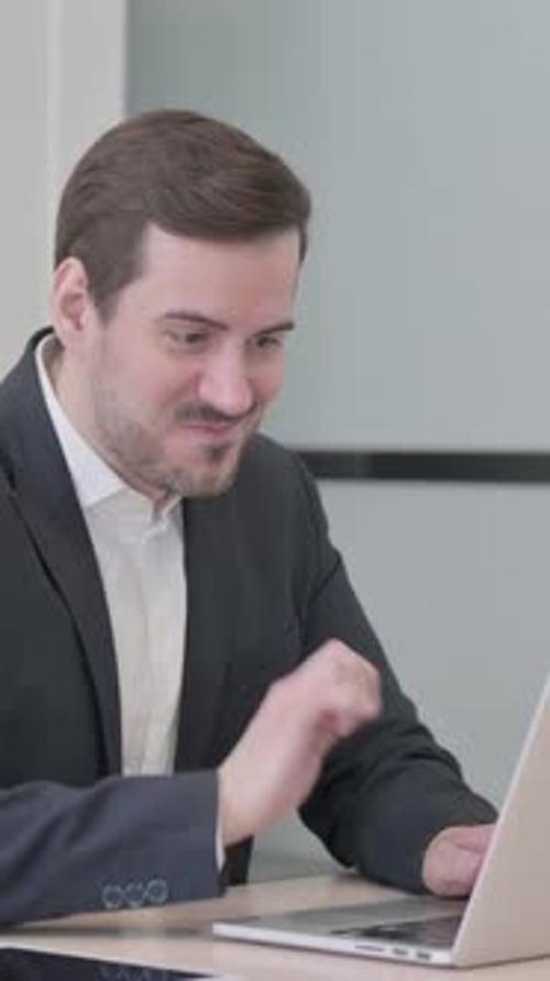 Businessman Celebrating Online Success on Laptop in Office, vertical video
