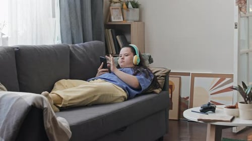 Young Adult Relaxing, Using Phone on Sofa