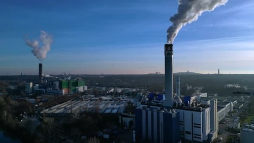 Waste to energy plant chimney emitting smoke into blue sky. Best aerial view drone