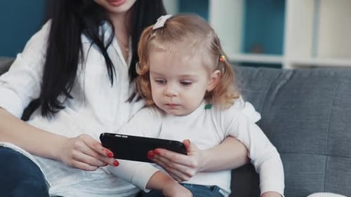 Mother and Daughter Looking at Mobile Phone on Couch
