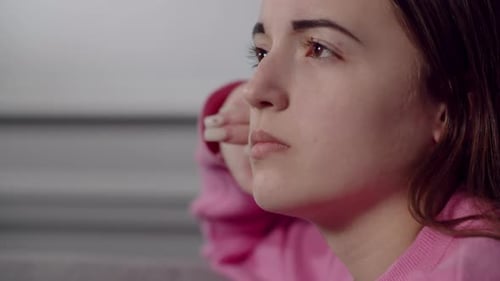 A Pretty European or American Young Lady with a Thoughtful Sad Gaze Downcasts Eyes and Looks Into