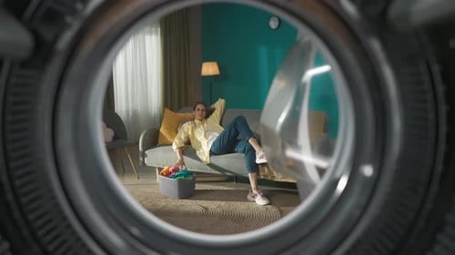 View From Inside the Empty Washing Machine Young Couple Having Fun Time While Doing Laundry