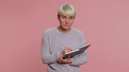 Young Adult Writing in a Notebook, Light Pink Backdrop