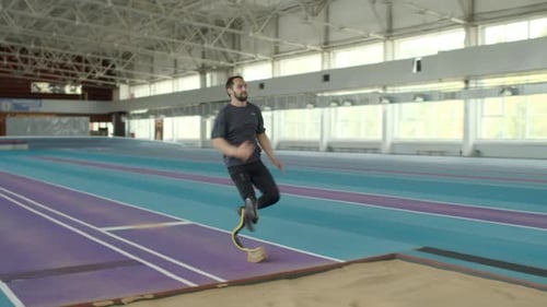 Athlete with Prosthetic Leg Performs Long Jump Indoors