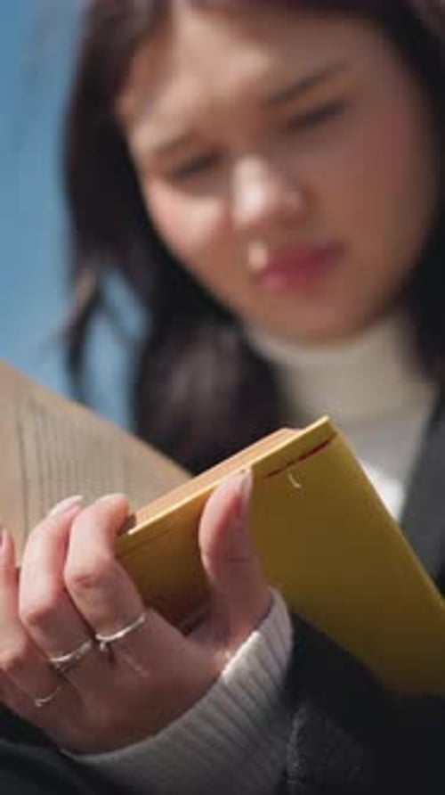 Gros plan d'un étudiant contemplant en lisant un livre jaune en plein soleil