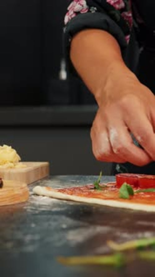 Woman preparing tasty pizza at home, adding fish to pizza base. Vertical video
