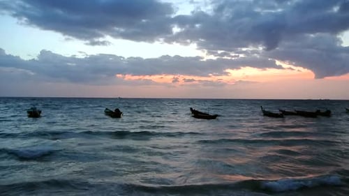 Serene fishing boats floating on the sea bathed by a colourful sunset