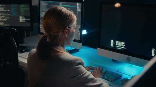 Woman Typing Code at Computer Workstation at Night