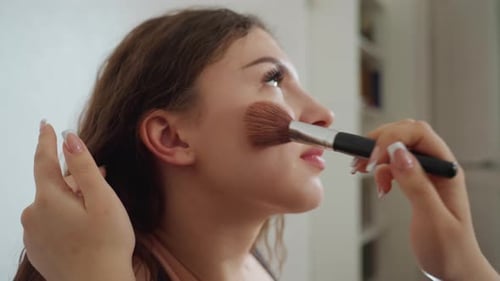 Woman Applies Makeup with Brush in Bright Light