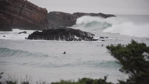 Surfers Riding Waves at a Rocky Beach
