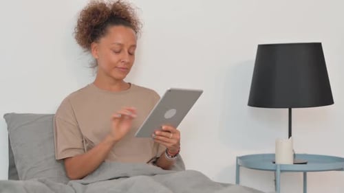 Woman Using Tablet in Bed at Home