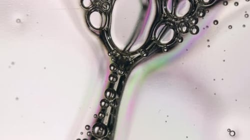 Bolhas de sabão translúcido descem lentamente em um pano de fundo branco abstrato. De perto, Macro