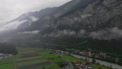 Aerial Cinematic Forward Through Fog Towards Dolomites Village and Mountains