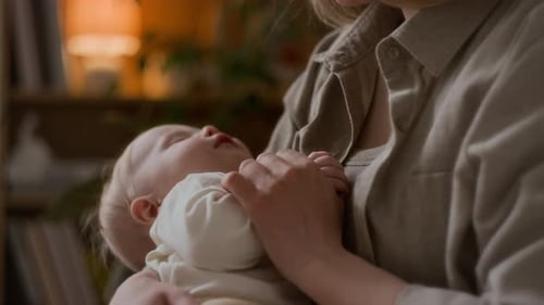 Mother Holding Sleeping Infant Inside Home