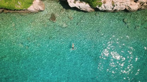 Solo Woman Swimmer in Pristine Waters of Croatia's Makarska Riviera. The clear azure sea sparkles un