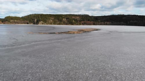 Aerial over frozen lake driftwood ice cold water winter cloudy sky day