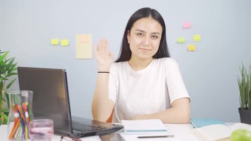 Smiling Woman Waving During Video Call at Desk