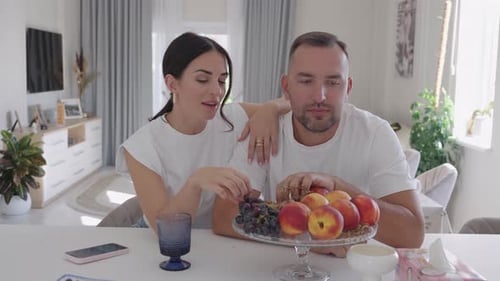 Loving Couple Sharing Grapes in Bright Kitchen