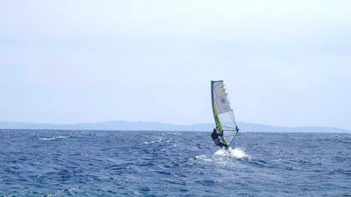 A man is engaged in windsurfing in the red sea, mountains in the background, water sport
