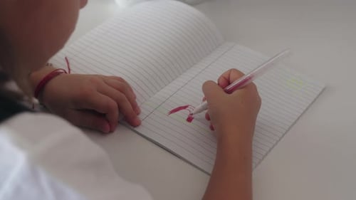Young Girl Drawing in Notebook at Table