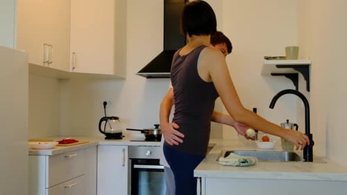 Affectionate Couple Prepares Food Together in Kitchen