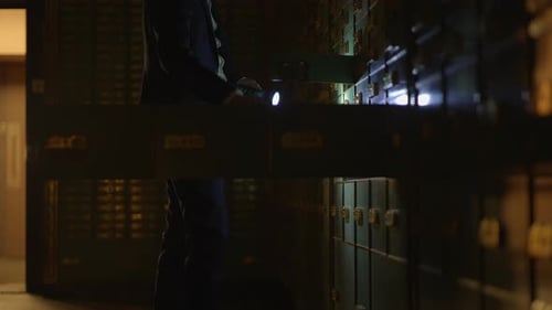 Man with Flashlight Opening Bank Safe Deposit Box