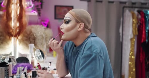 Adult applies bright lipstick at a vanity