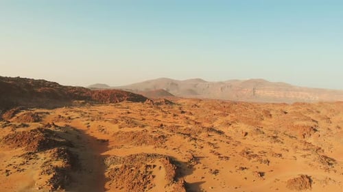 Desert volcanic landscape in red. Stones and a mountain with a volcano.