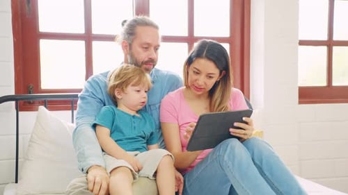 Family Uses Tablet Together on Bed Indoors